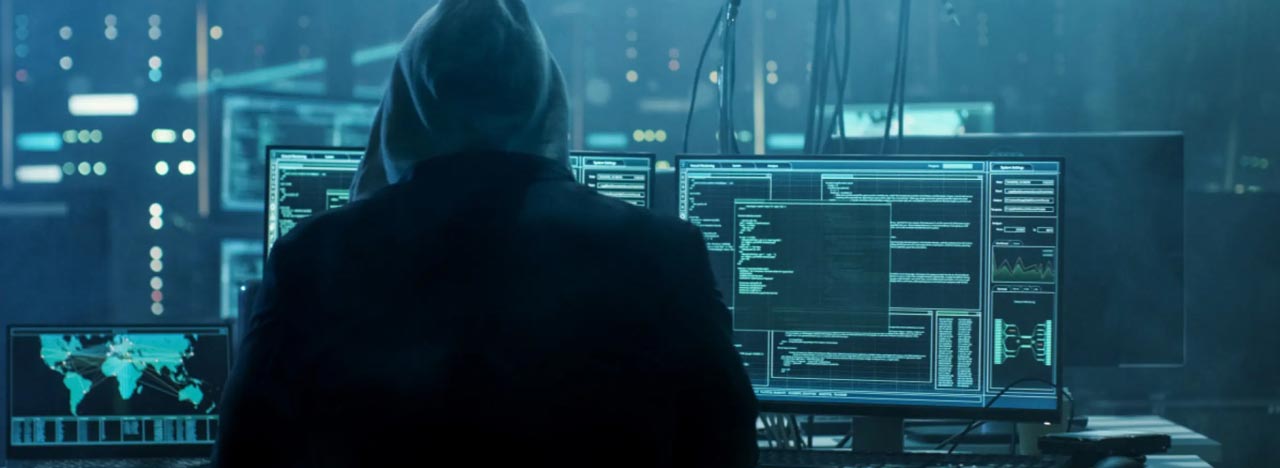 A hacker sits turned away at a computer
