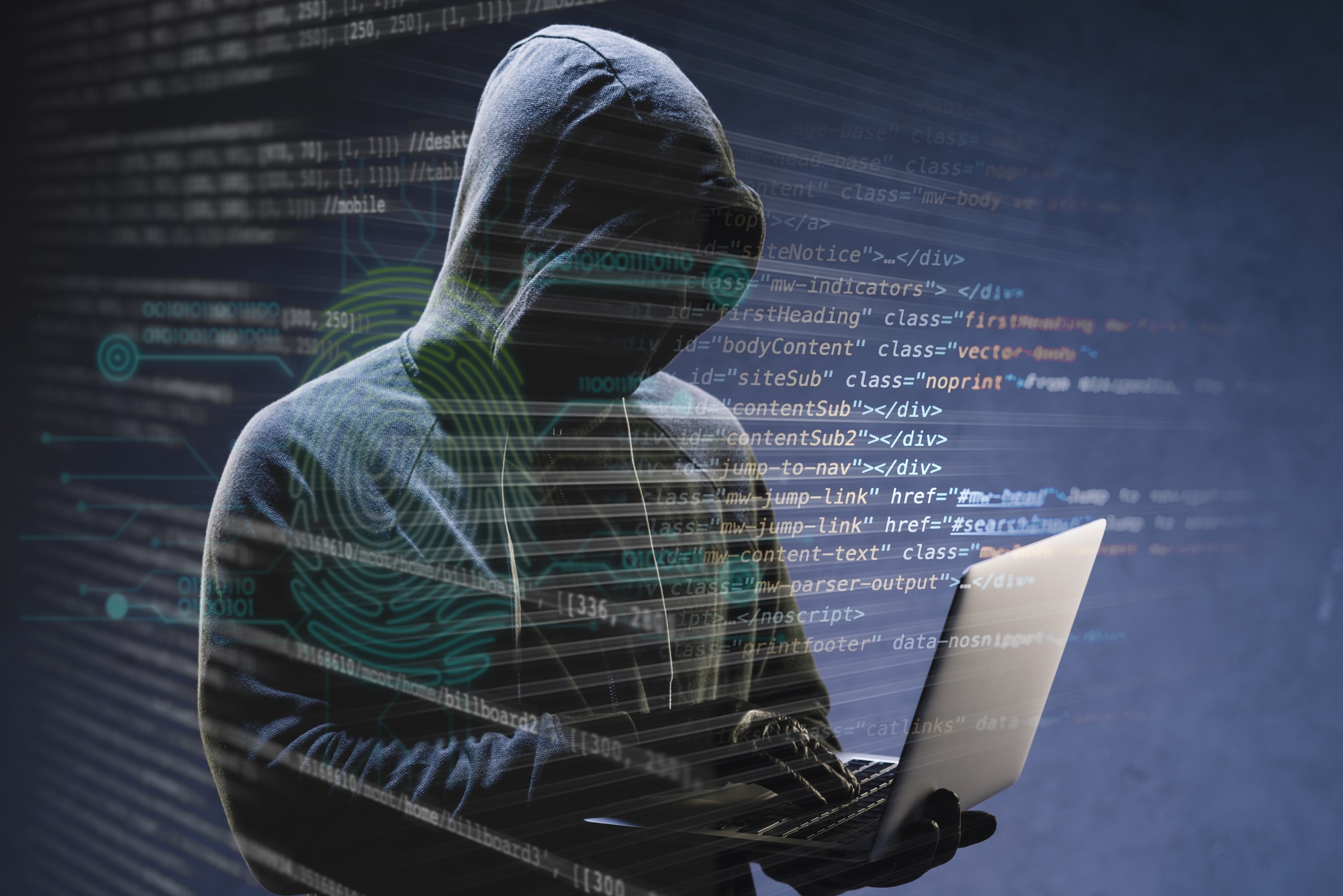 A hacker sits turned away at a computer
